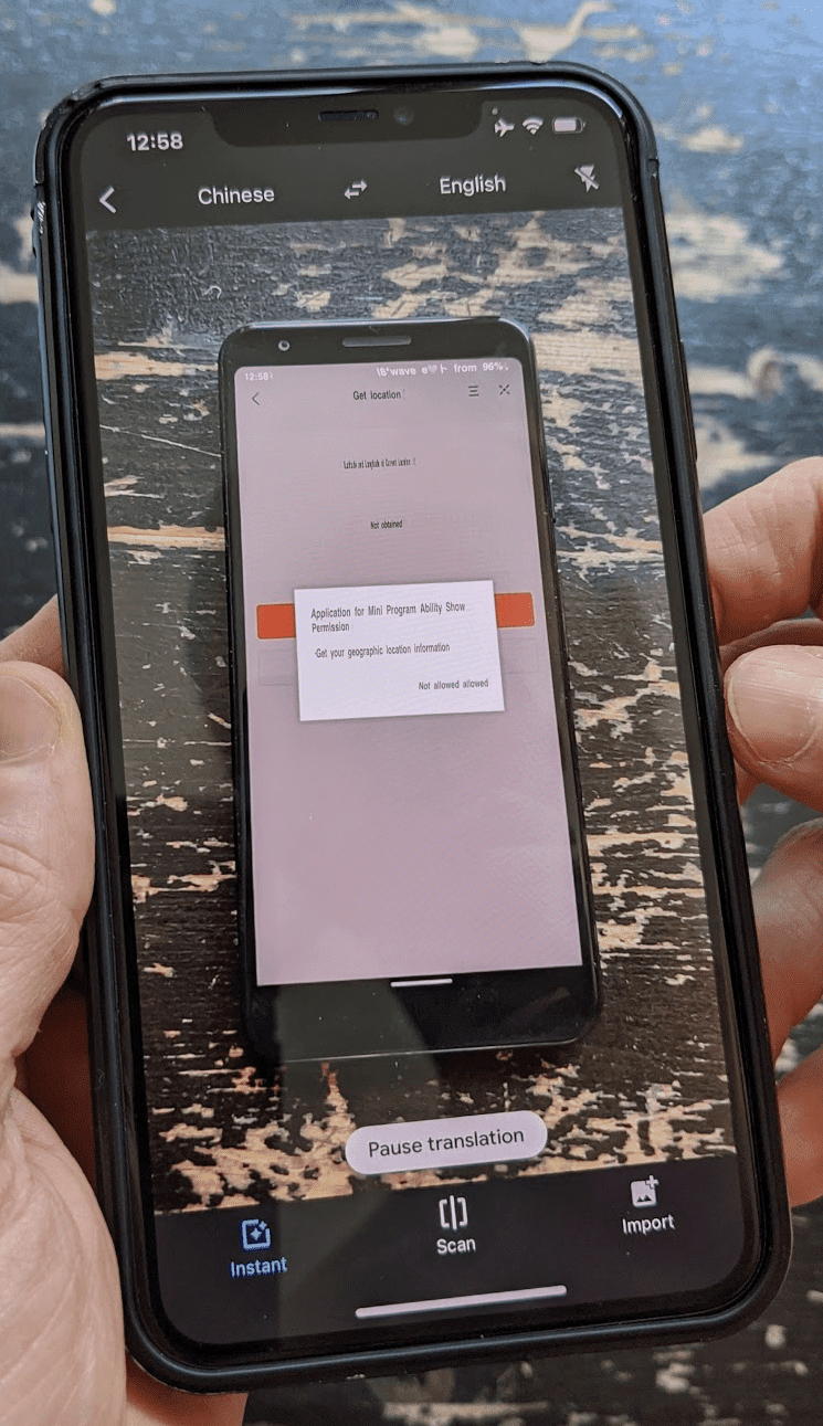 Ponsel sekunder yang menjalankan Google Terjemahan dalam mode kamera yang menerjemahkan langsung antarmuka pengguna aplikasi mini berbahasa China yang berjalan di ponsel utama.