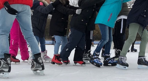 Throng of feet of ice skating people.