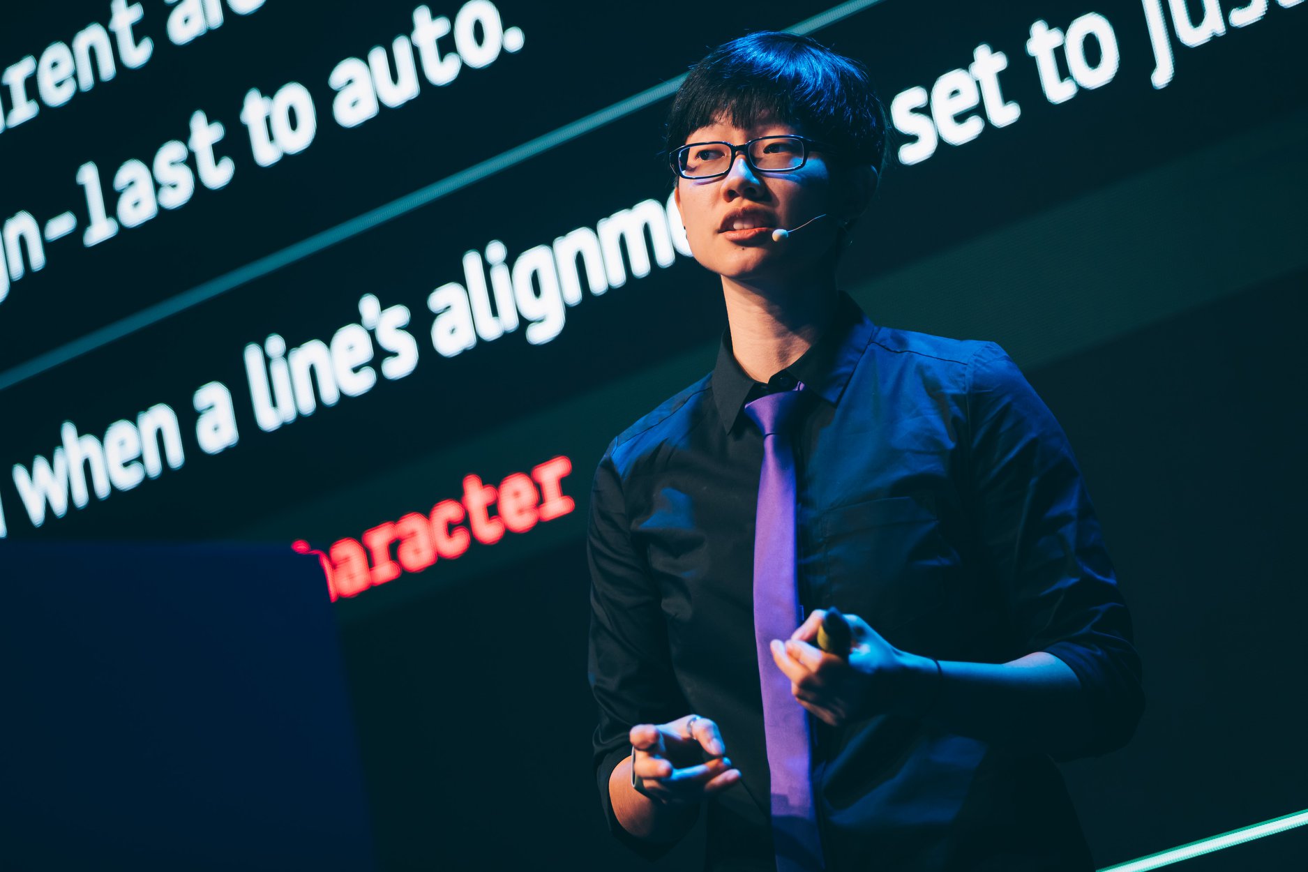 Chen Hui Jing speaking on stage on front of a large screen showing slides.